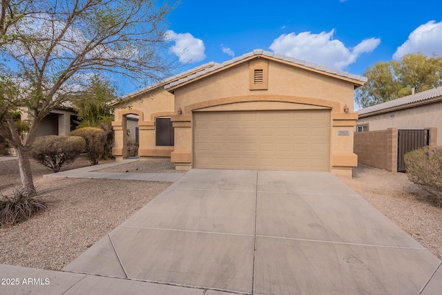 mediterranean / spanish-style home with driveway, an attached garage, fence, and stucco siding