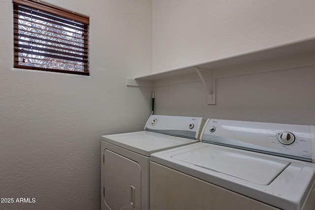 clothes washing area featuring laundry area, washer and clothes dryer, and a textured wall