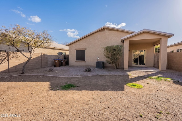 rear view of house with central air condition unit, a fenced backyard, a patio, and stucco siding