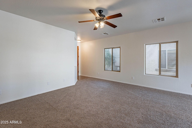 spare room with visible vents, dark carpet, baseboards, and ceiling fan