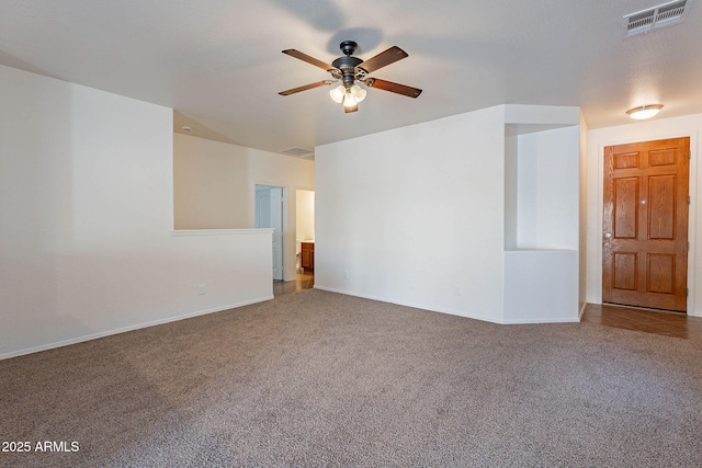 carpeted empty room with baseboards, visible vents, and a ceiling fan