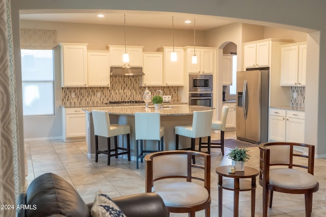 kitchen featuring decorative light fixtures, white cabinetry, light stone countertops, and appliances with stainless steel finishes