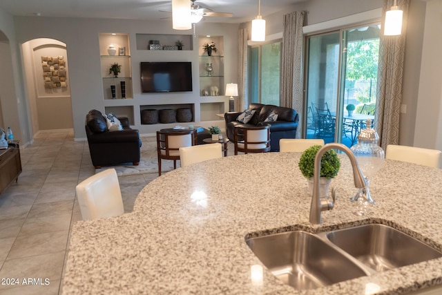 27002 W Oraibi Dr, Buckeye, AZ 85396 - kitchen with light stone counters, pendant lighting, built in shelves, and a sink