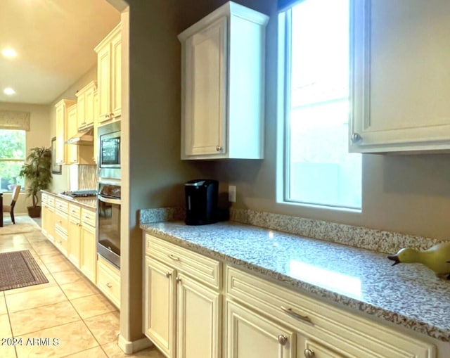 kitchen with light stone countertops, stainless steel appliances, and light tile patterned floors