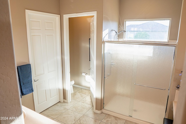 bathroom with tile patterned floors, toilet, and a shower with shower door