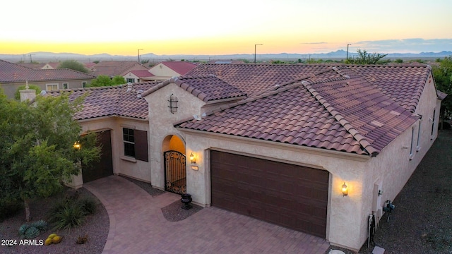 27002 W Oraibi Dr, Buckeye, AZ 85396 - mediterranean / spanish-style home with decorative driveway, an attached garage, a tiled roof, and stucco siding