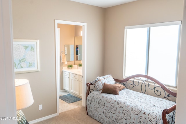 bedroom with ensuite bathroom and light carpet