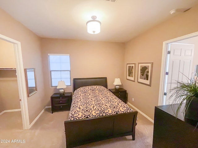 bedroom with light colored carpet, a walk in closet, and a closet