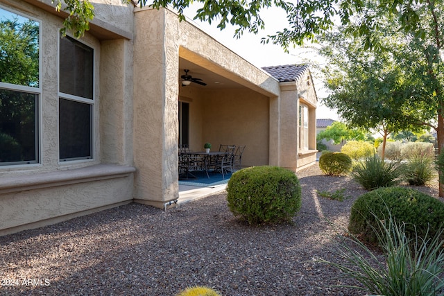 27002 W Oraibi Dr, Buckeye, AZ 85396 - view of side of home featuring stucco siding, a ceiling fan, a patio, and outdoor dining area