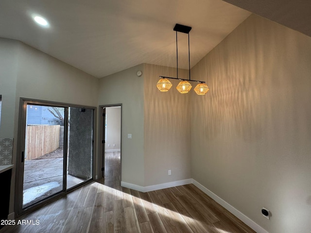 empty room featuring an inviting chandelier, dark hardwood / wood-style flooring, and vaulted ceiling