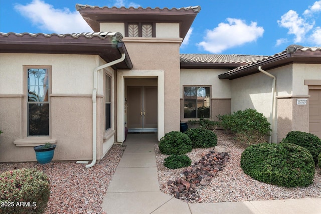 view of exterior entry featuring a tile roof and stucco siding