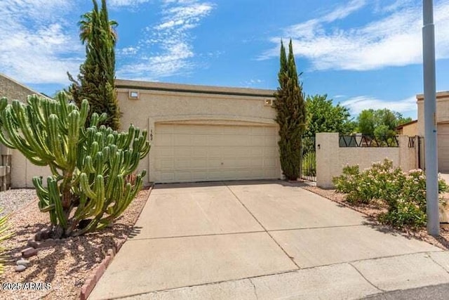 garage with a gate, concrete driveway, and fence