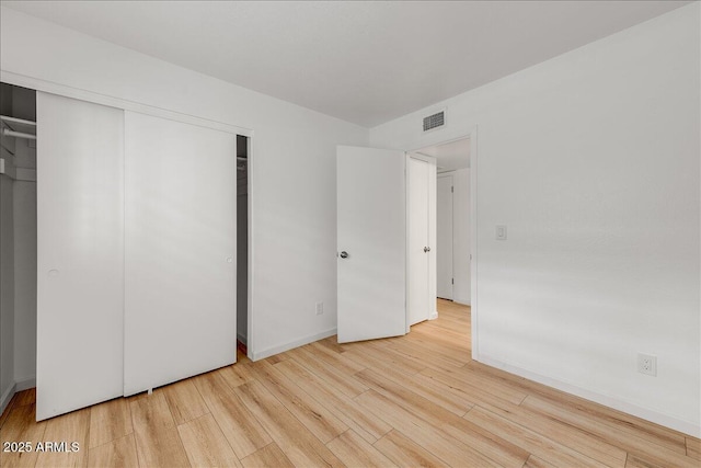 unfurnished bedroom with visible vents, baseboards, a closet, and light wood finished floors