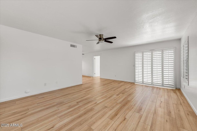 unfurnished room featuring light wood-style floors, a ceiling fan, visible vents, and baseboards