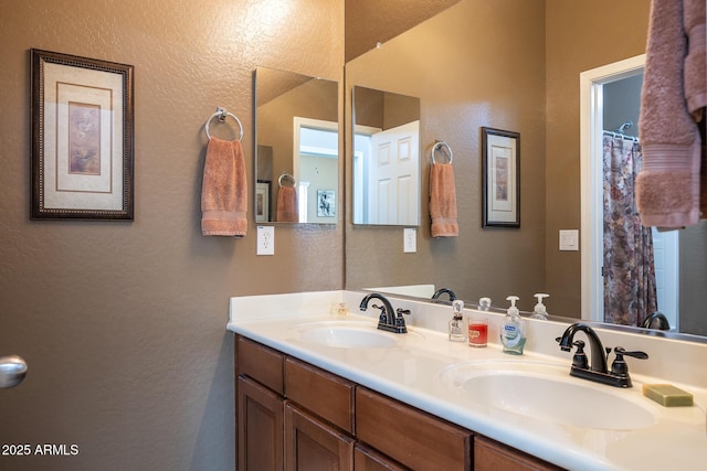 bathroom featuring a textured wall, a sink, and double vanity