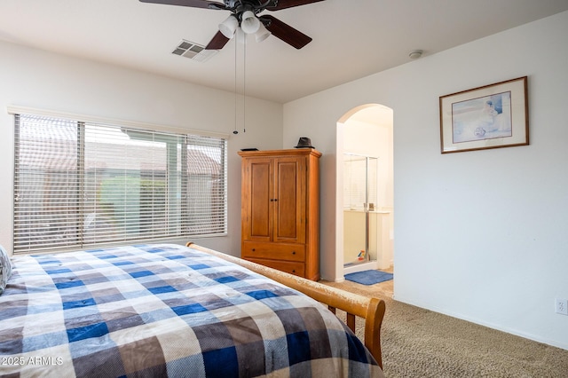 carpeted bedroom with a ceiling fan, arched walkways, visible vents, and ensuite bathroom