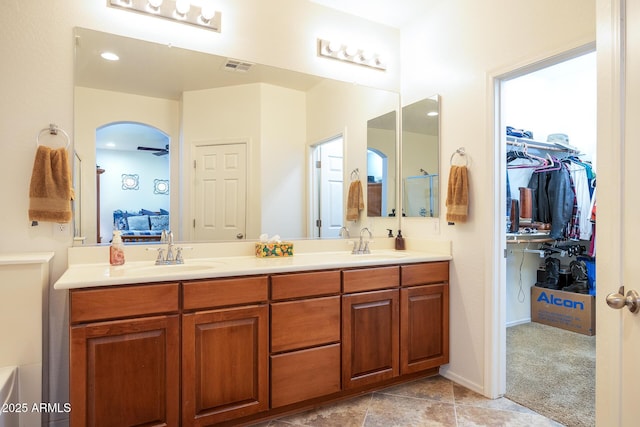 bathroom with double vanity, visible vents, a walk in closet, and a sink