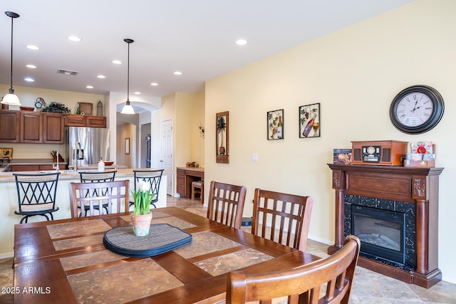 dining room featuring arched walkways, visible vents, a high end fireplace, and recessed lighting