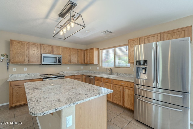 kitchen with sink, light tile patterned floors, appliances with stainless steel finishes, a kitchen island, and a breakfast bar area