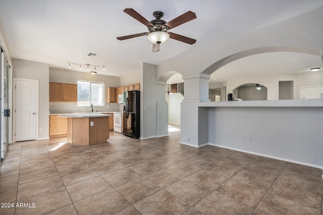 kitchen featuring light tile patterned floors, black fridge with ice dispenser, a center island, and ceiling fan