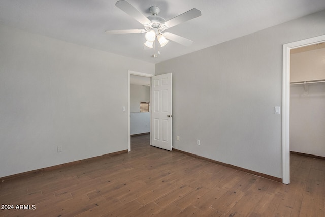 unfurnished bedroom featuring hardwood / wood-style flooring, a spacious closet, ceiling fan, and a closet