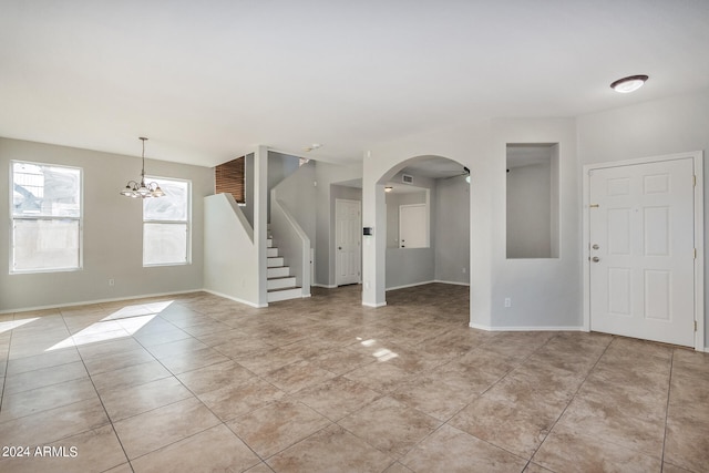 empty room featuring a notable chandelier and light tile patterned floors