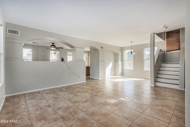 tiled empty room with ceiling fan with notable chandelier