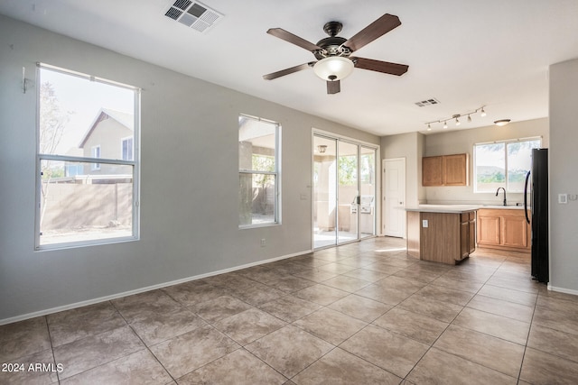 kitchen featuring a center island, ceiling fan, light tile patterned floors, and black fridge