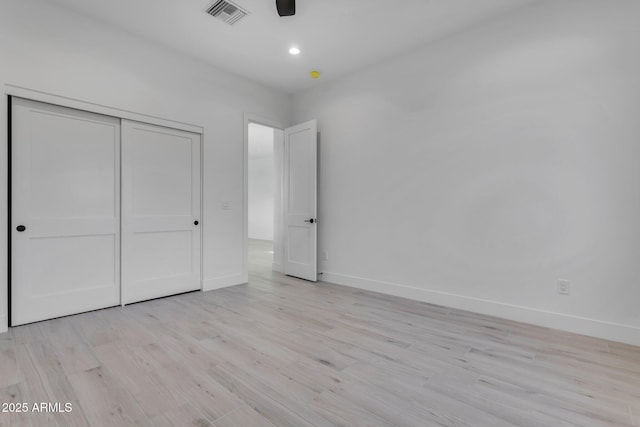 unfurnished bedroom with baseboards, visible vents, light wood-style flooring, recessed lighting, and a closet