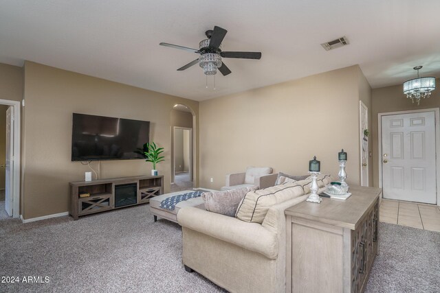 living room with light colored carpet and ceiling fan with notable chandelier