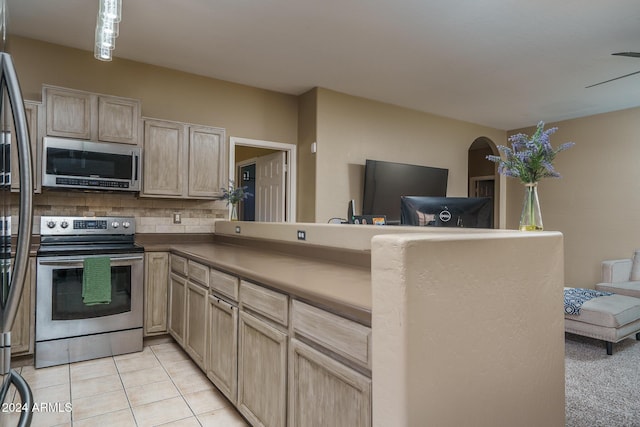 kitchen featuring kitchen peninsula, appliances with stainless steel finishes, backsplash, and light tile patterned flooring