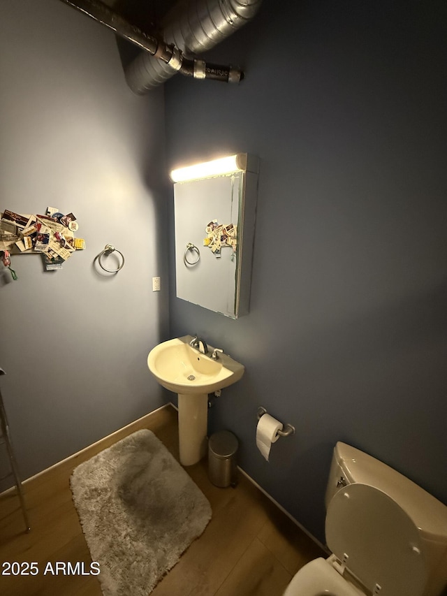 bathroom with wood finished floors, toilet, and baseboards