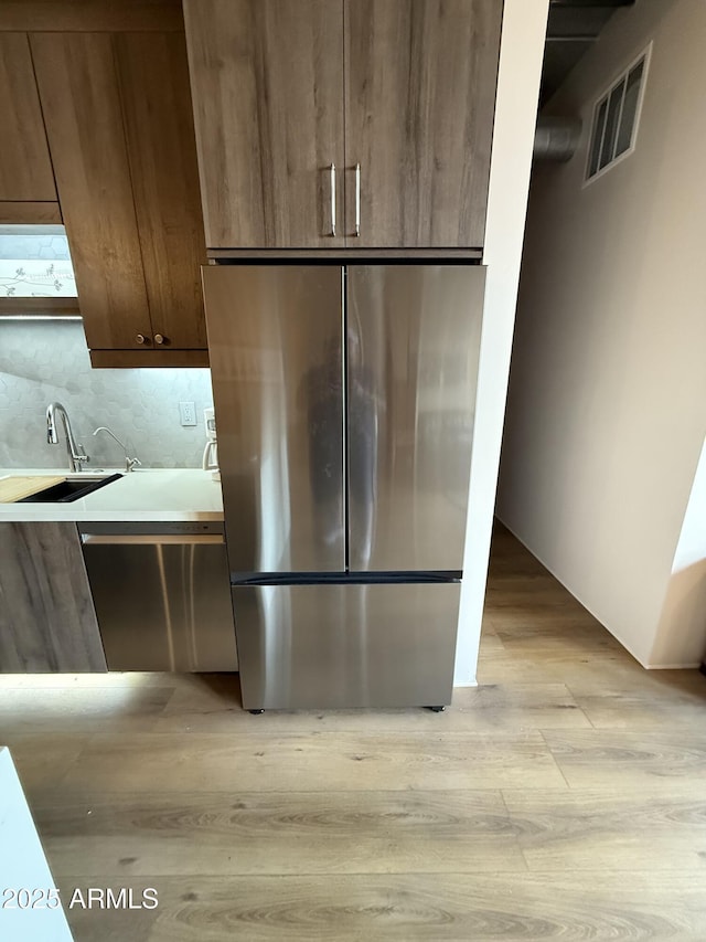 kitchen with visible vents, modern cabinets, stainless steel appliances, light wood-style floors, and a sink