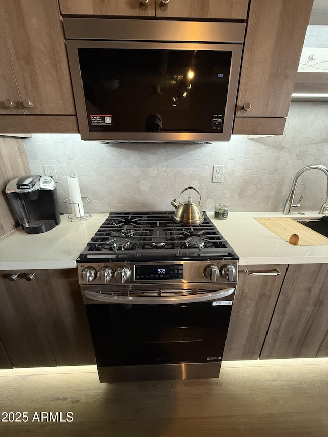 kitchen featuring stainless steel appliances, light countertops, and backsplash