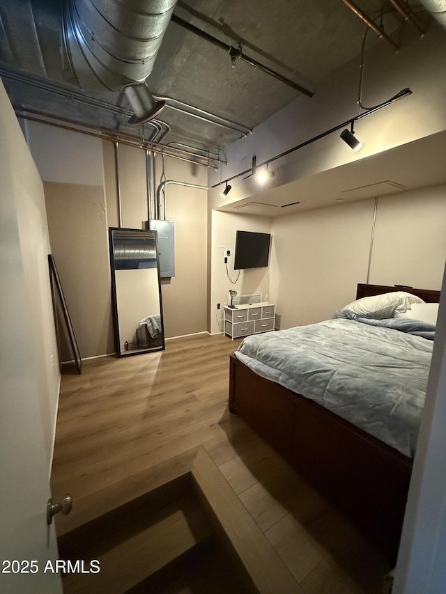 bedroom featuring electric panel and wood finished floors