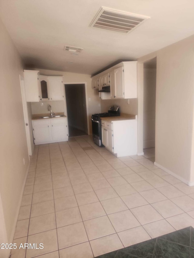 kitchen with light tile patterned floors, stainless steel gas range oven, visible vents, and a sink