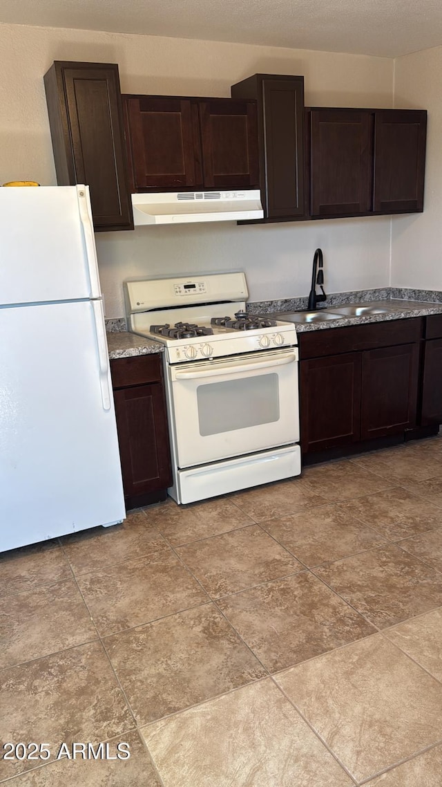 kitchen with under cabinet range hood, dark brown cabinets, a sink, and white appliances