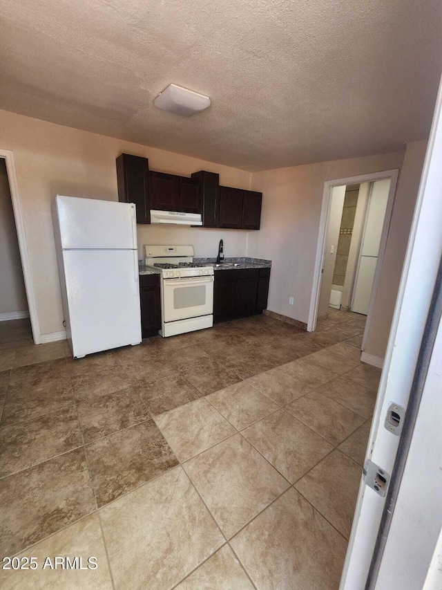 kitchen with under cabinet range hood, a textured ceiling, white appliances, and baseboards