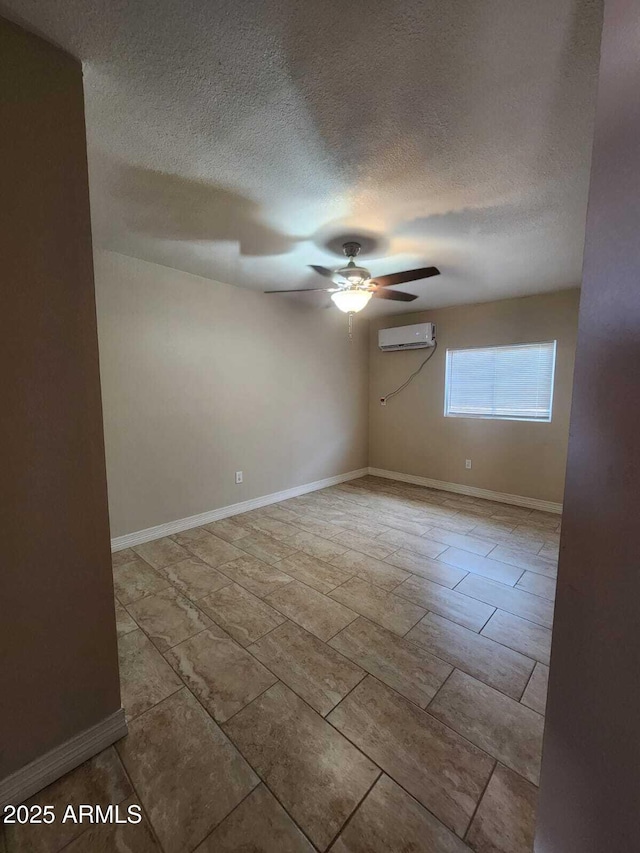 unfurnished room featuring a wall unit AC, a textured ceiling, baseboards, and a ceiling fan