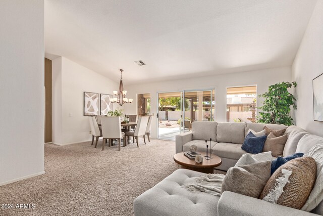 carpeted living room with a notable chandelier and vaulted ceiling