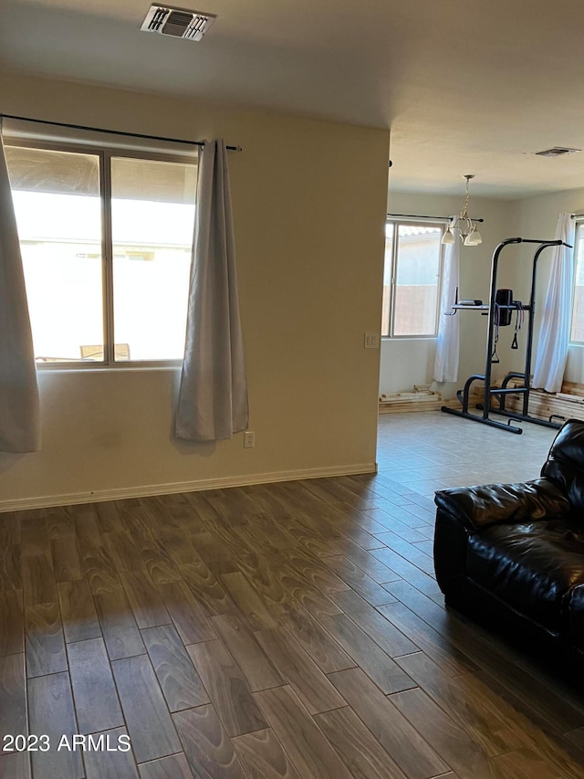 unfurnished living room with an inviting chandelier and dark wood-type flooring