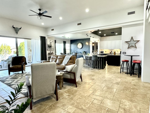 living area featuring a ceiling fan, stone tile flooring, visible vents, and recessed lighting