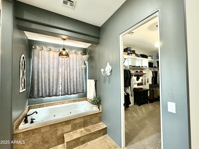 full bathroom with a jetted tub, a spacious closet, and visible vents