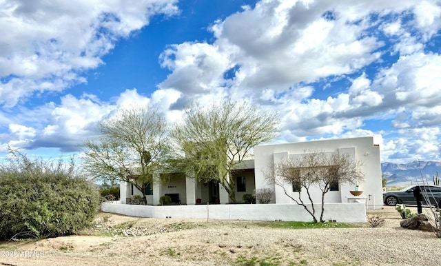 rear view of property with a fenced front yard and stucco siding