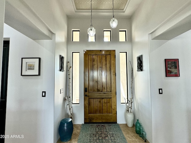 foyer entrance with a tray ceiling and a high ceiling