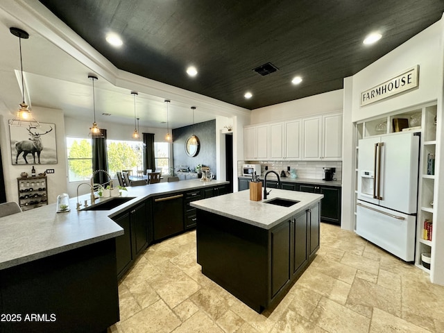 kitchen featuring a large island with sink, dark cabinets, white appliances, a sink, and stone tile flooring