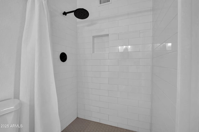 bathroom with a tile shower and toilet