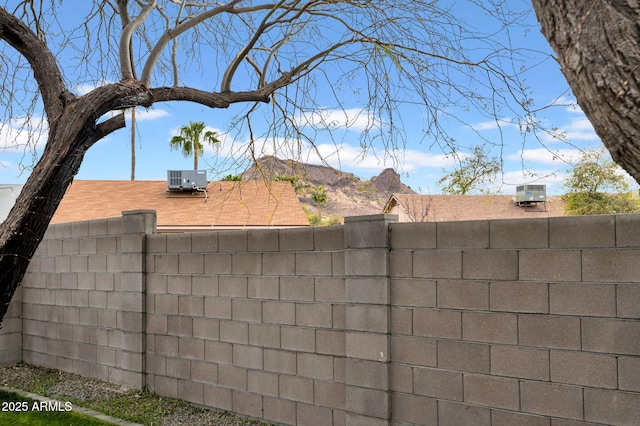 view of yard with central AC, fence, and a mountain view