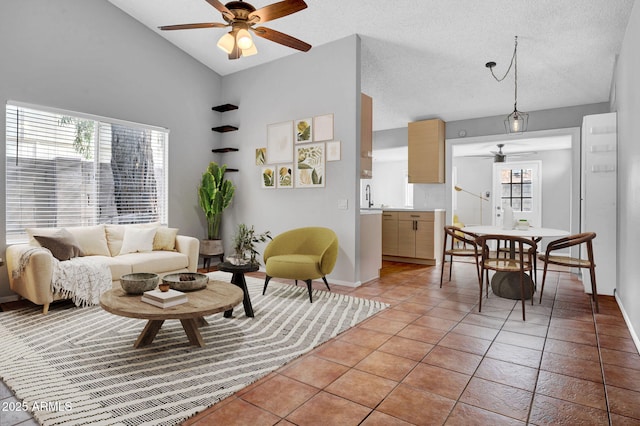 living room with light tile patterned floors, a textured ceiling, a ceiling fan, and baseboards