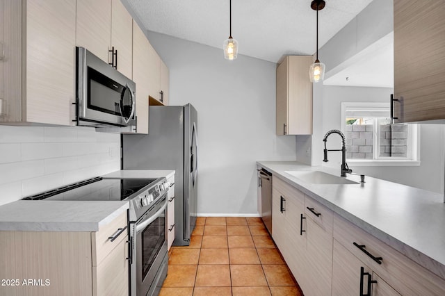 kitchen featuring light tile patterned floors, appliances with stainless steel finishes, a sink, light countertops, and backsplash